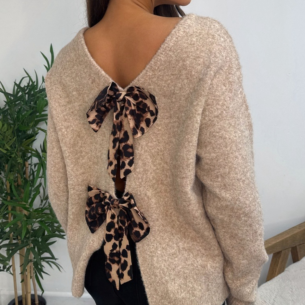 Close up wholesale women’s beige knit jumper with leopard print bow back detail worn by model. Soft brushed texture long sleeve sweater from AW25 wholesale collection for retail buyers